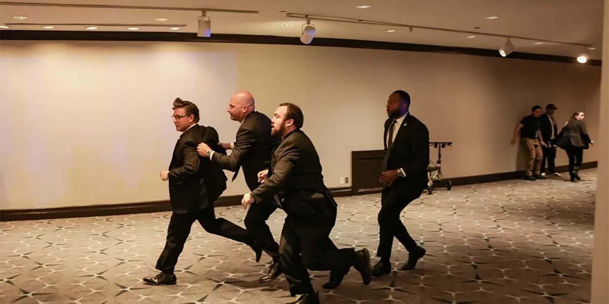 People ducking under tables during a scene of panic at a formal political dinner